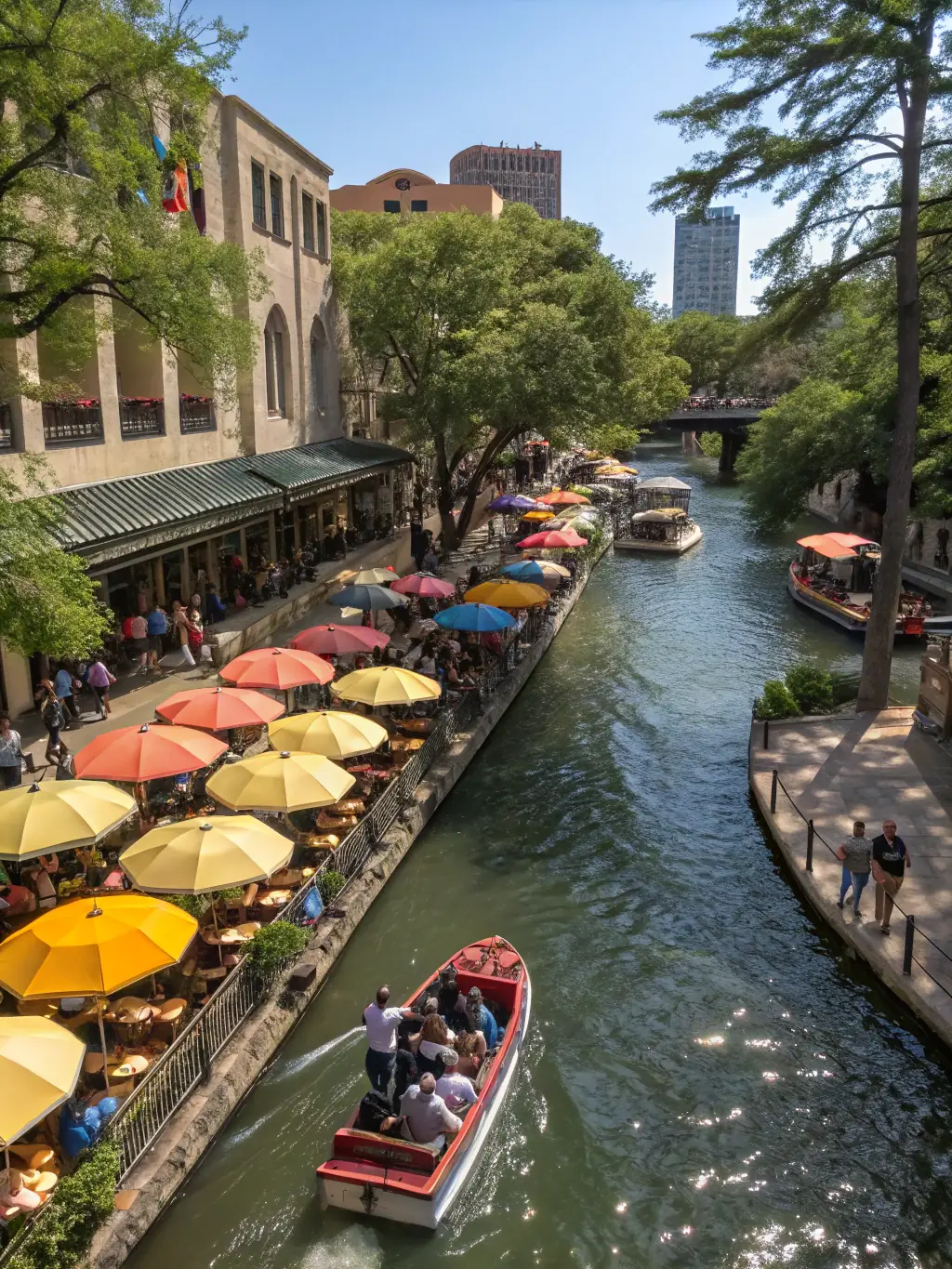 A picturesque view of the San Antonio Riverwalk, highlighting the lush greenery, pedestrian walkways, and the unique architecture of the surrounding buildings.